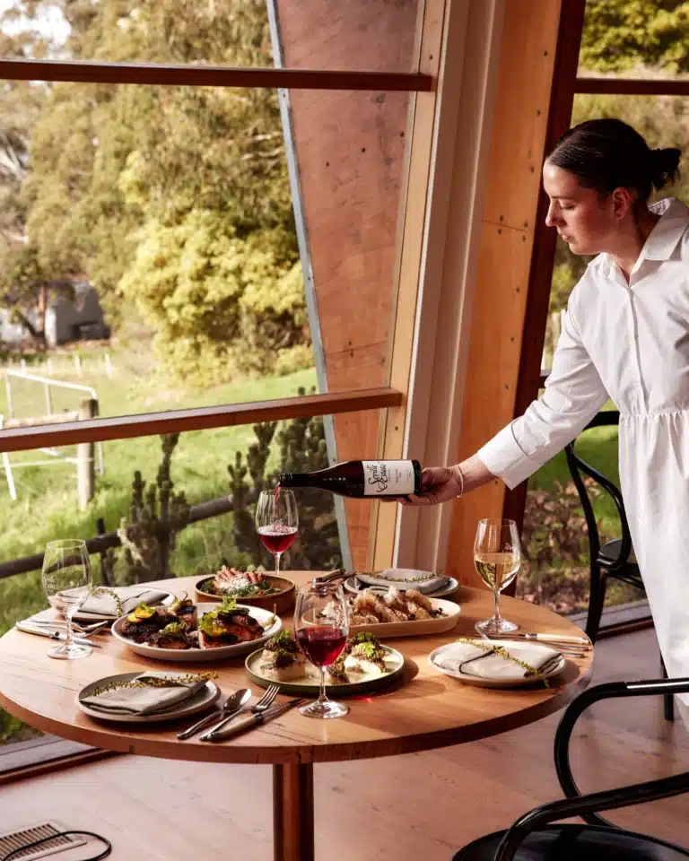 A server pouring local wine at a table overlooking the vines