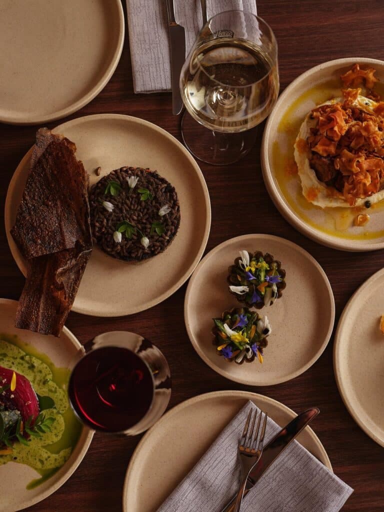 A shared table of plated dishes and local wine